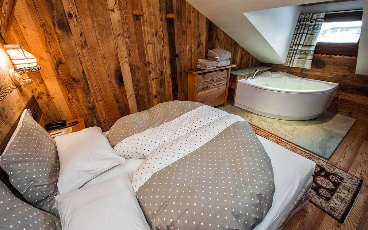 Camera da letto rustica con vasca idromassaggio, pareti in legno e letto accogliente.