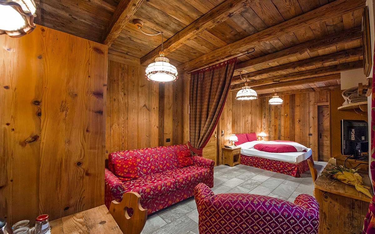 Accogliente camera in legno con divano, letto matrimoniale e decorazioni rustiche.