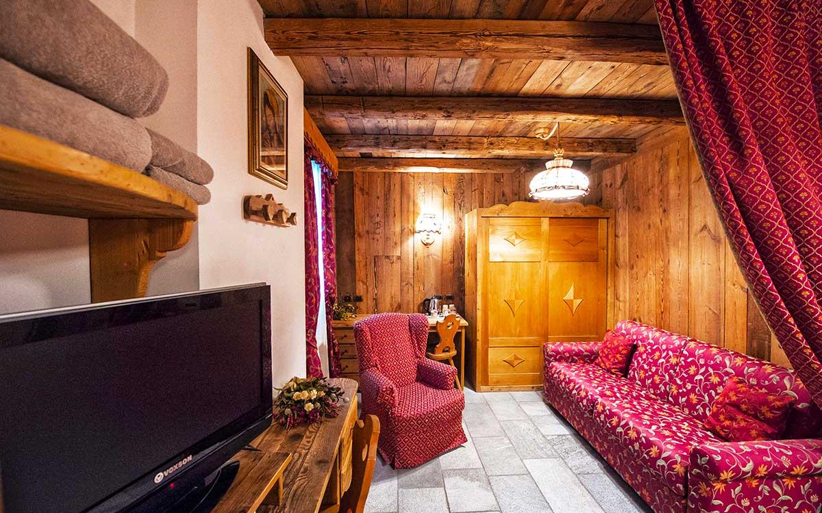 Accogliente soggiorno rustico con mobili in legno e tessuti rossi decorati.