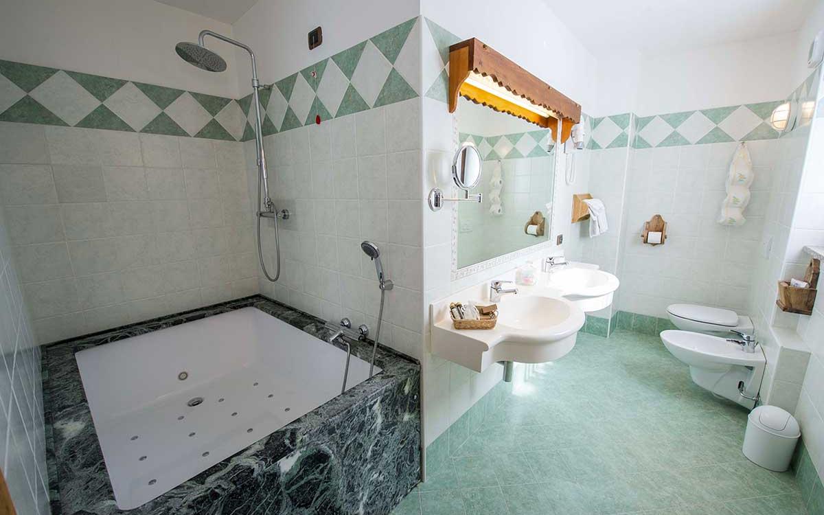 Bagno moderno con vasca idromassaggio, doppio lavabo, bidet e specchio grande.