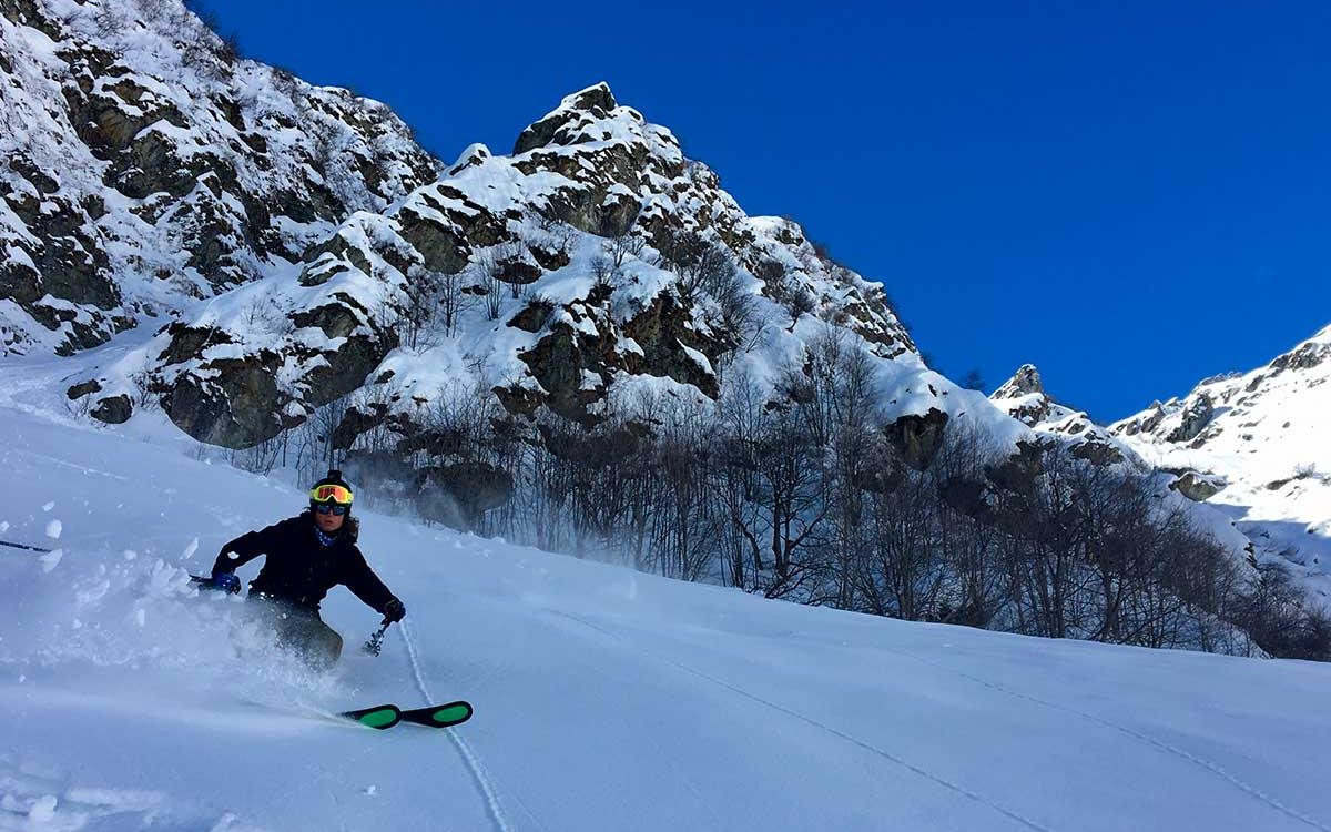 Sciare tra le montagne innevate sotto un cielo blu intenso.