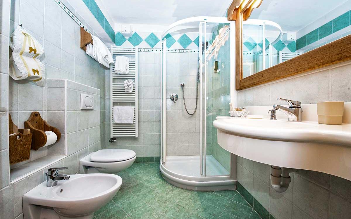 Bagno moderno con doccia, bidet, lavabo, wc e piastrelle verde acqua.