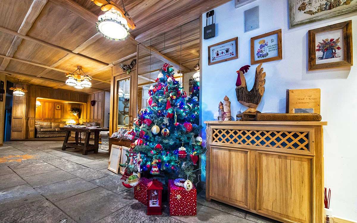 Salotto accogliente con albero di Natale decorato e arredi in legno.