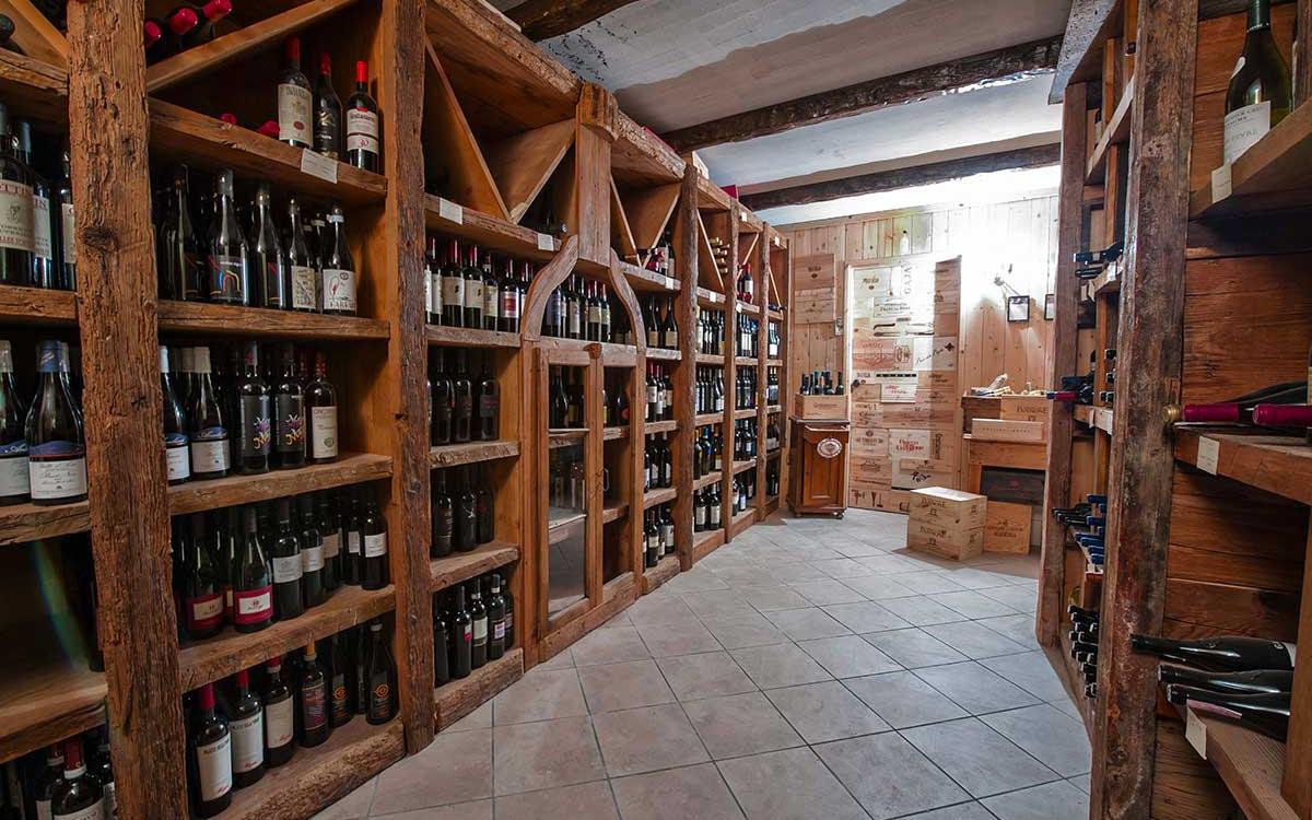 Cantina con scaffali di legno pieni di bottiglie di vino e casse di legno.