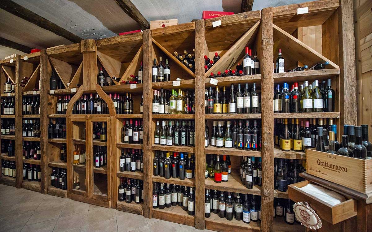 Scaffali in legno con una vasta selezione di bottiglie di vino in una cantina.