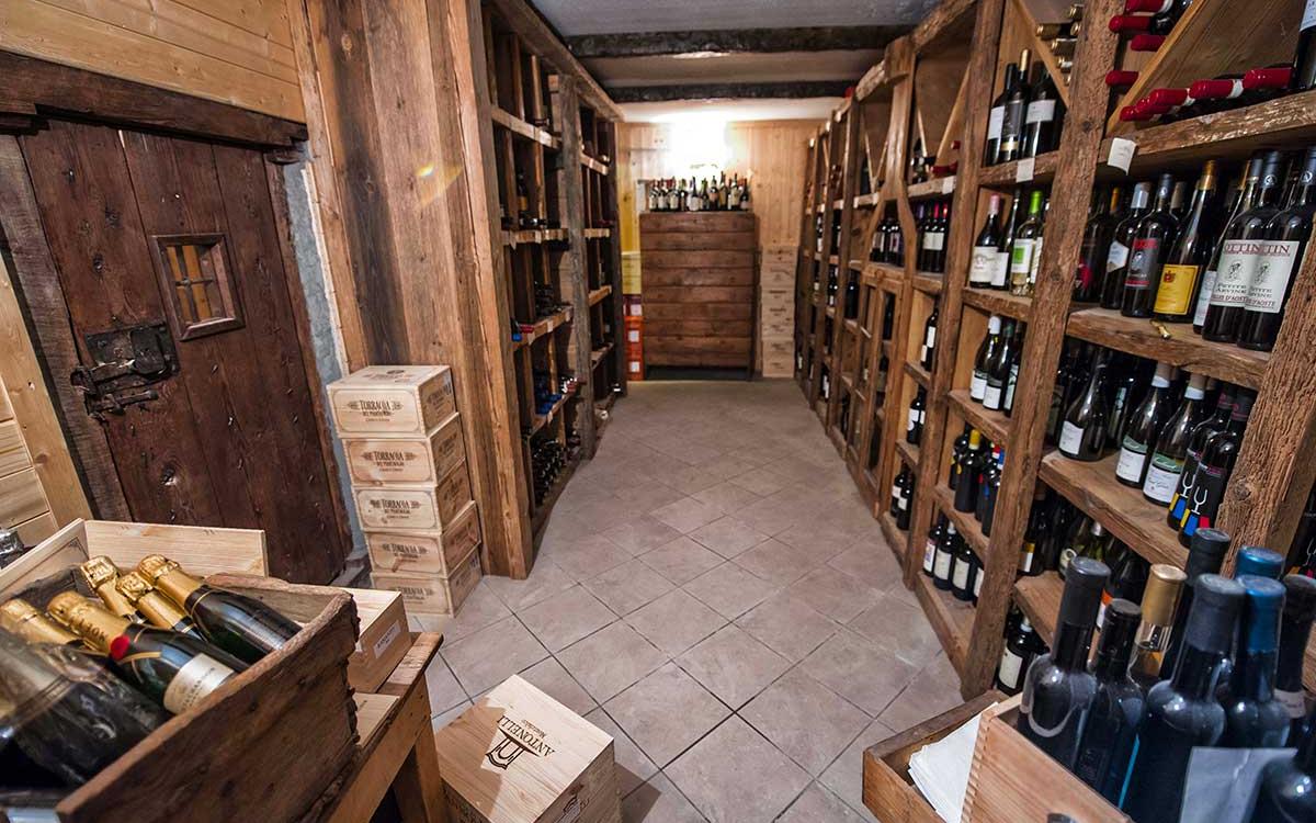 Cantina con scaffali in legno pieni di bottiglie di vino e casse di legno.