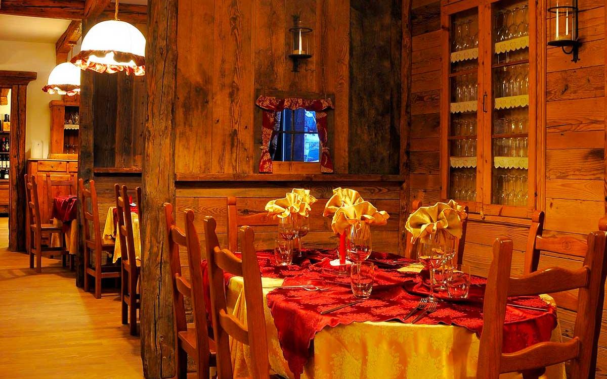 Accogliente ristorante con arredamento in legno e tovaglie rosse, atmosfera calda e rustica.