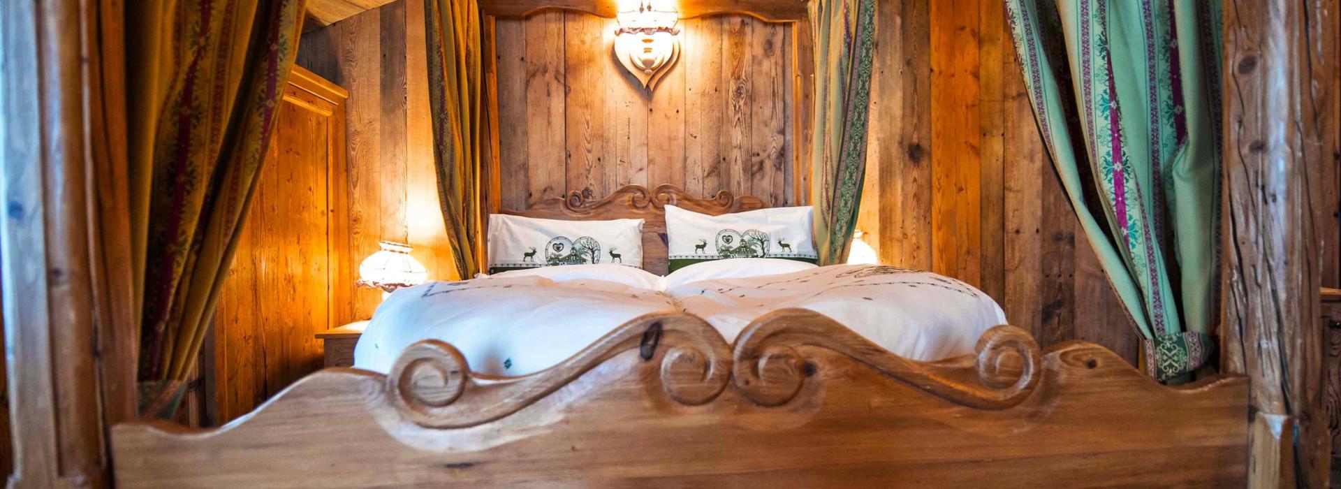 Camera da letto rustica con letto a baldacchino in legno e tende decorative.