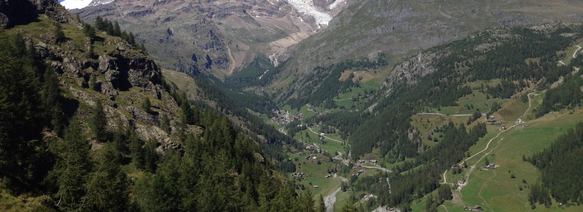 Panorama alpino con montagne innevate, cielo blu e vallate verdi.