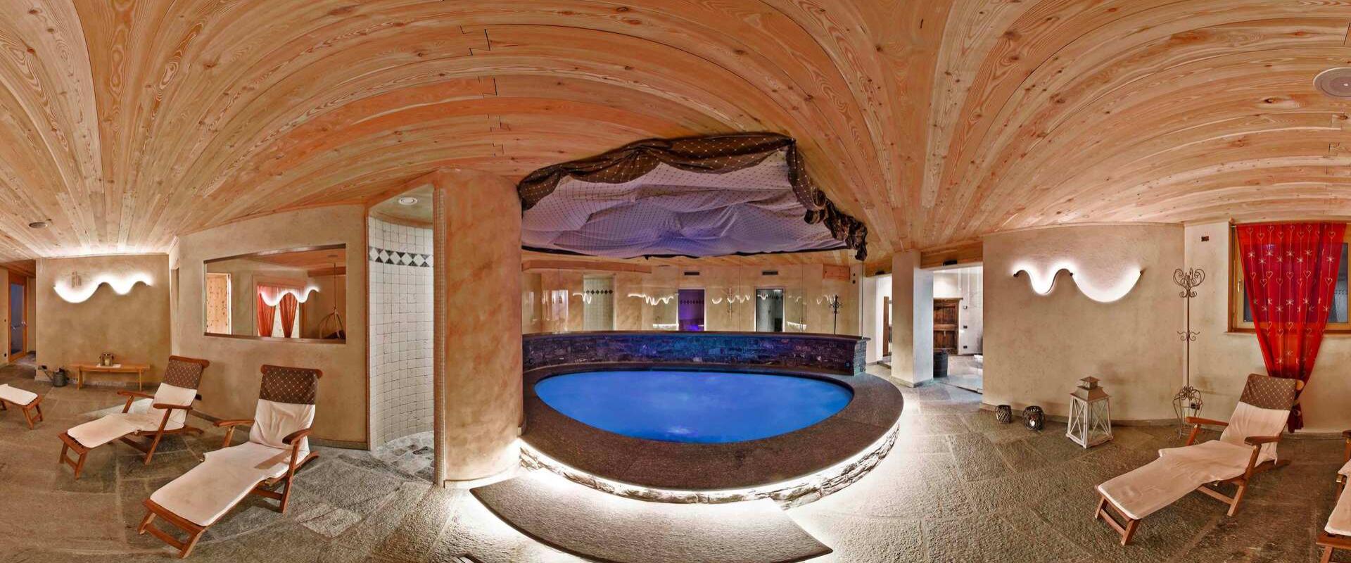 Centro benessere con piscina circolare, lettini e soffitto in legno.