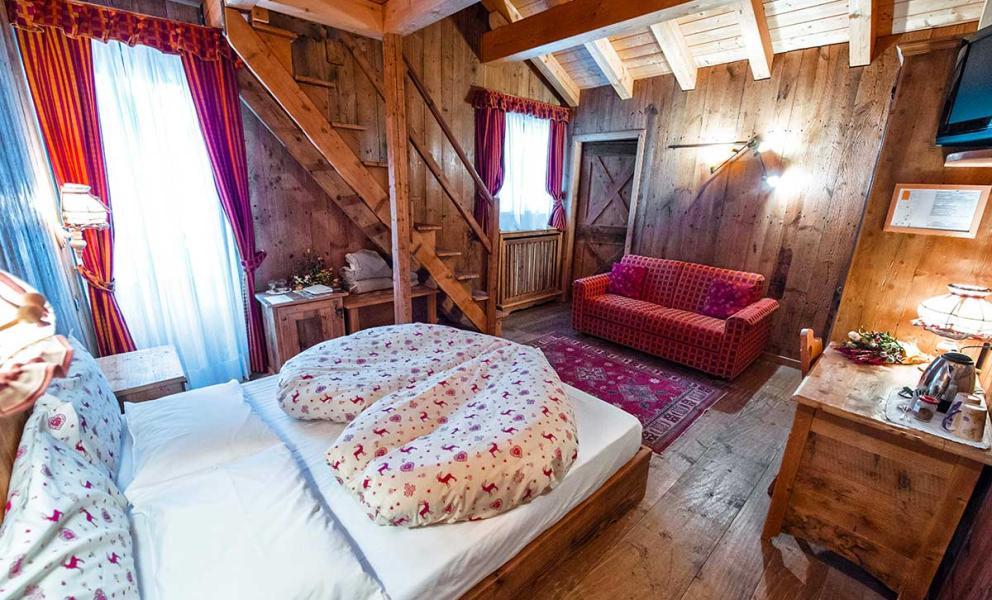 Camera accogliente con letto matrimoniale, divano, scala in legno e decorazioni rustiche.