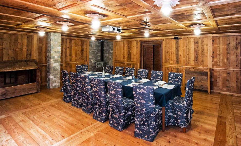 Sala riunioni rustica con tavolo centrale e sedie rivestite, decorata in legno.