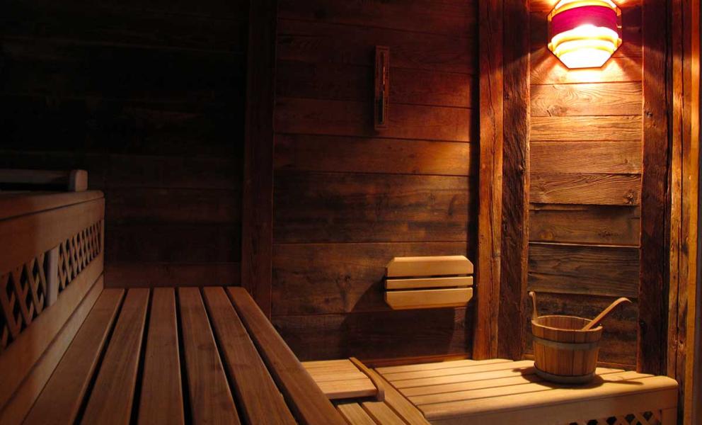 Una sauna in legno con panche e un secchio sotto una luce soffusa.