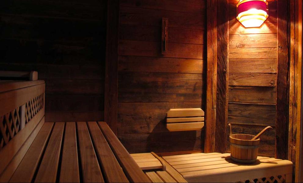 Sauna in legno con panche, secchio di legno e illuminazione soffusa.